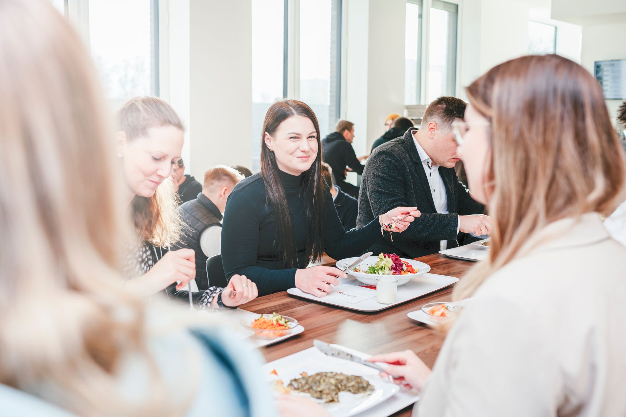 Mitarbeiter essen gemeinsam Mittag im Firmenrestaurant.