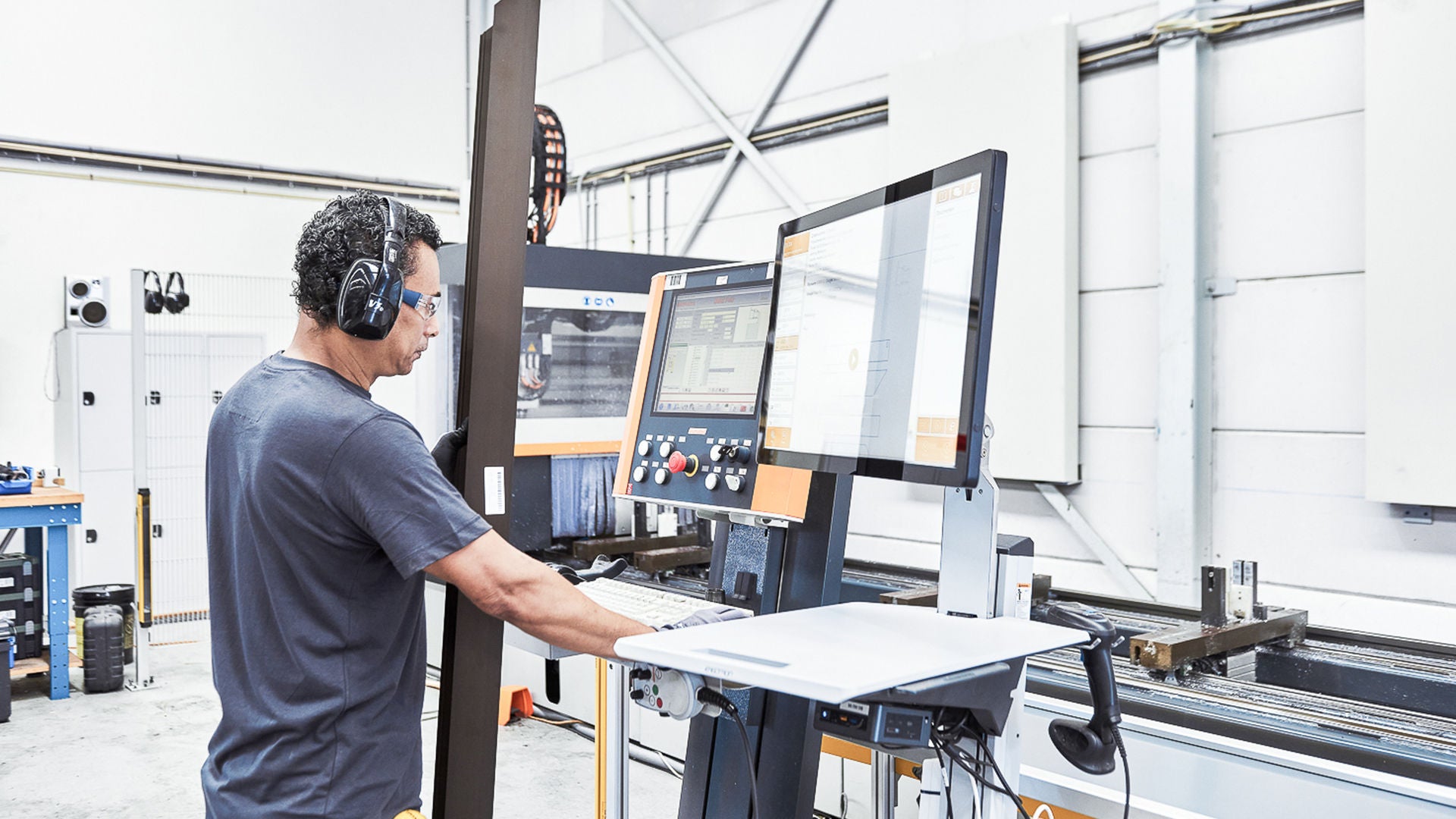 Ein Mann steht in einer Metallbauwerkstatt an einem Logikal MES-Terminal.