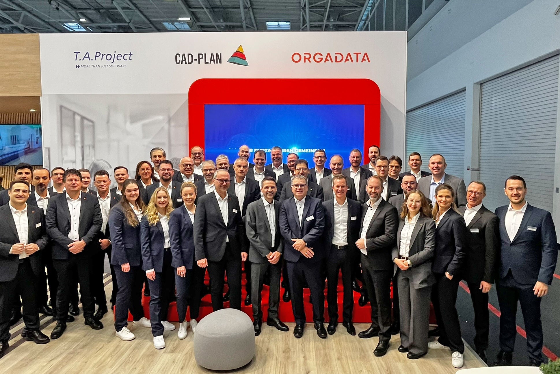 Group photograph featuring the Orgadata team in front of the exhibition stand at Bau 2025 in Munich.